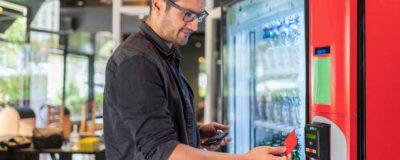 Man Selects Drink At Vending Machine And Pays With Credit Card